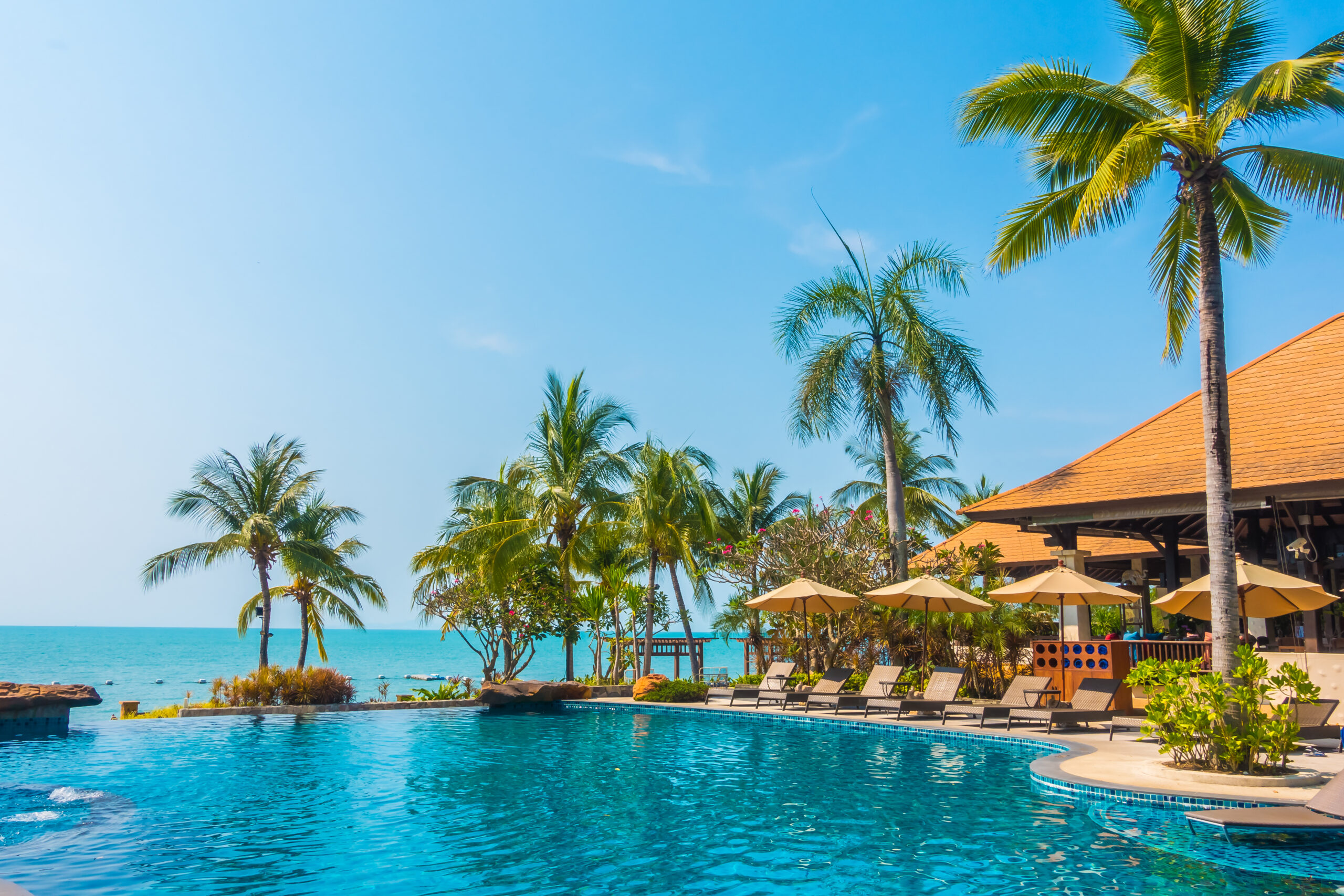 Beautiful luxury Swimming pool with palm tree and sea background in hotel pool resort - Boost up color Processing